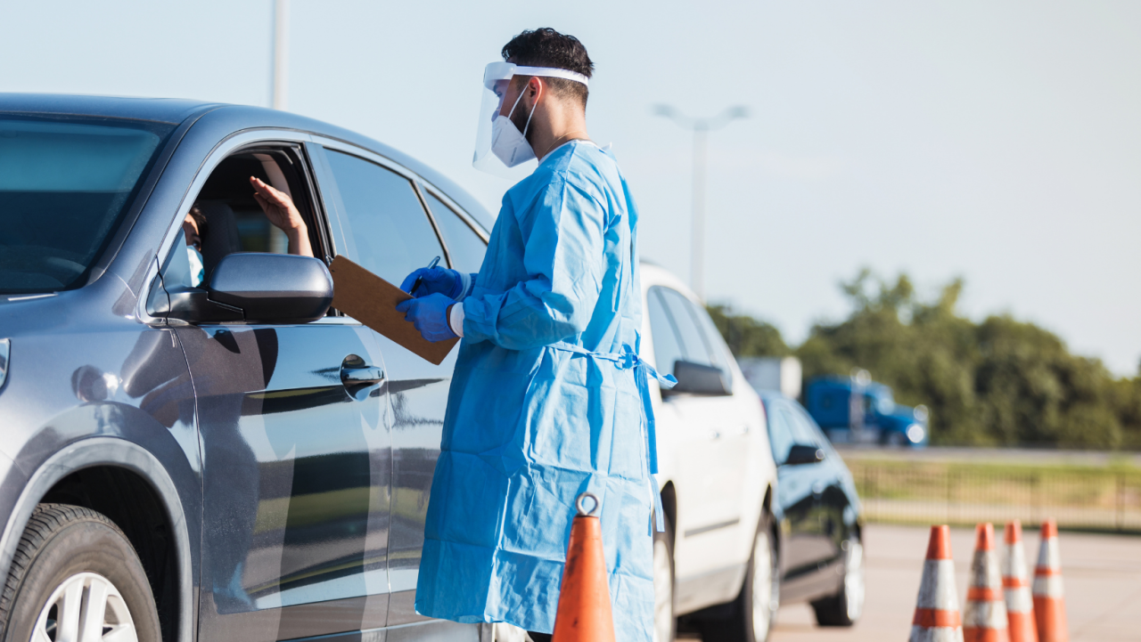 Man in PPE, administering testing in a drive-thru 