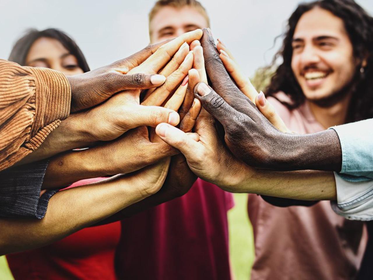 Group of diverse people pushing their hands into the center