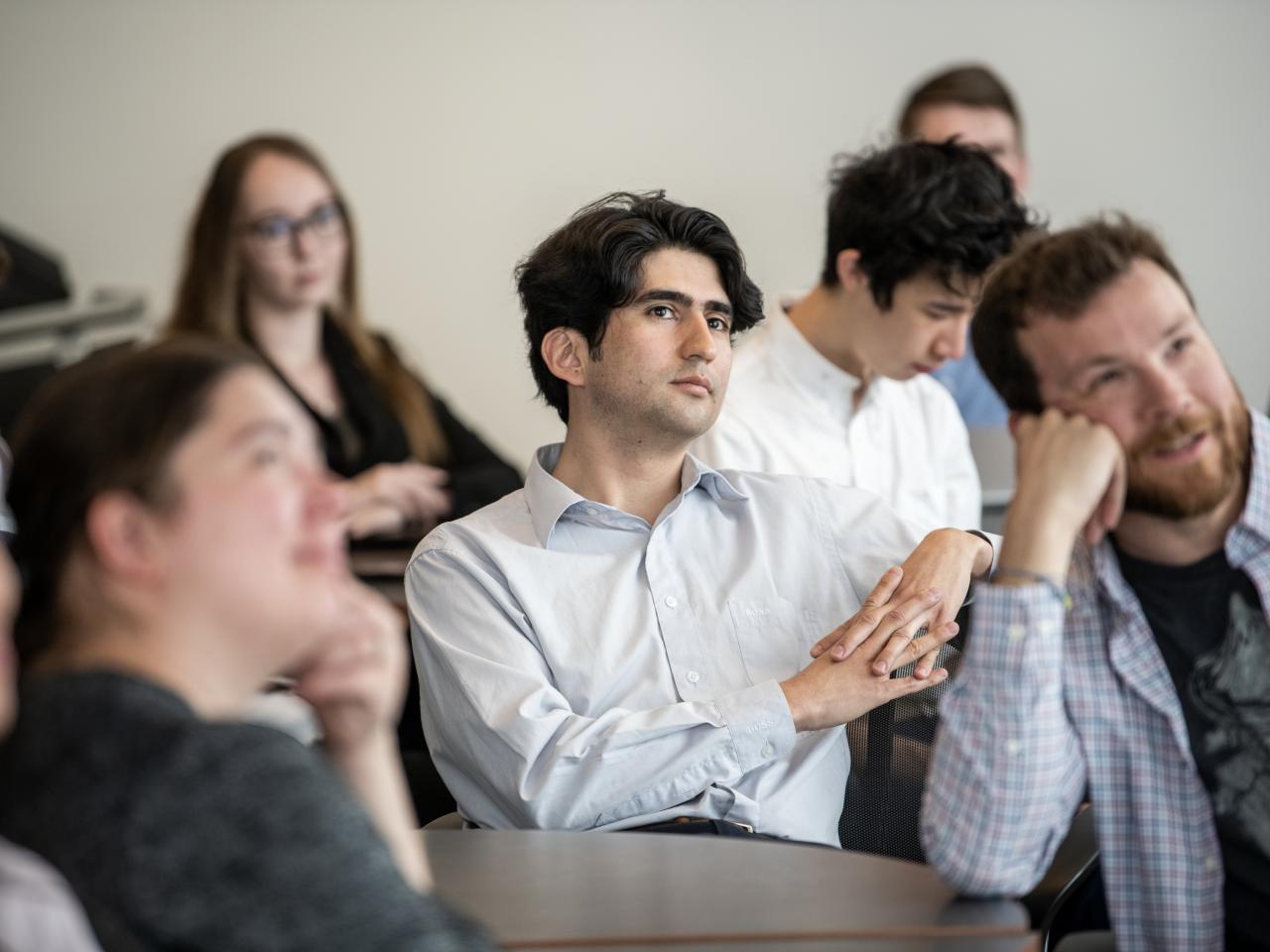 Group of students and professionals watching a presentation out of frame