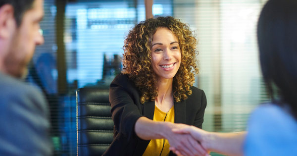 A woman shaking hands with a pair of interviewers across a table