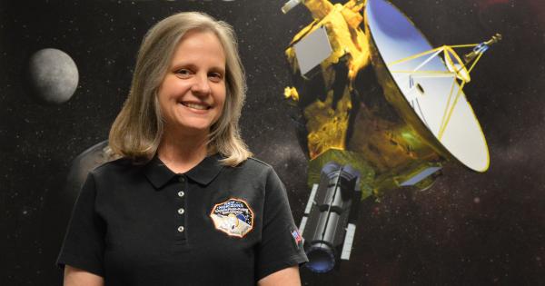 Alive Bowman standing in front of a picture of the New Horizons Satellite 