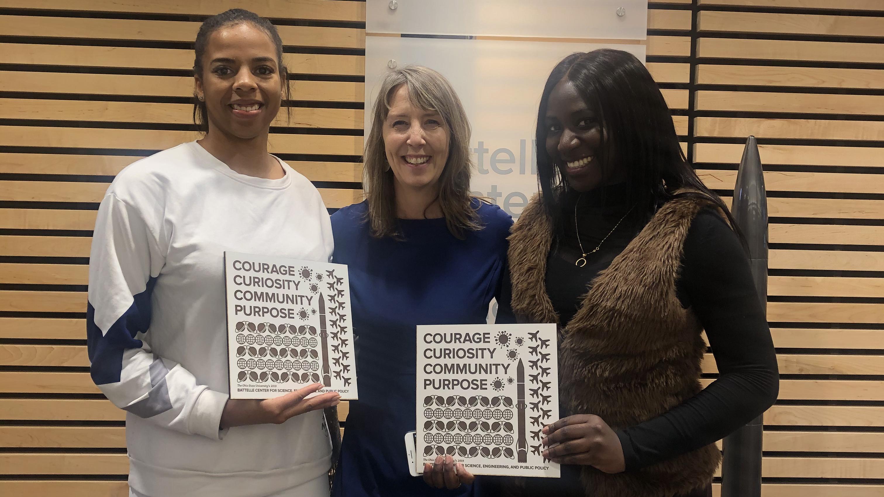 Dr. Newton surrounded by two alumni holding their 2019 graduation plates