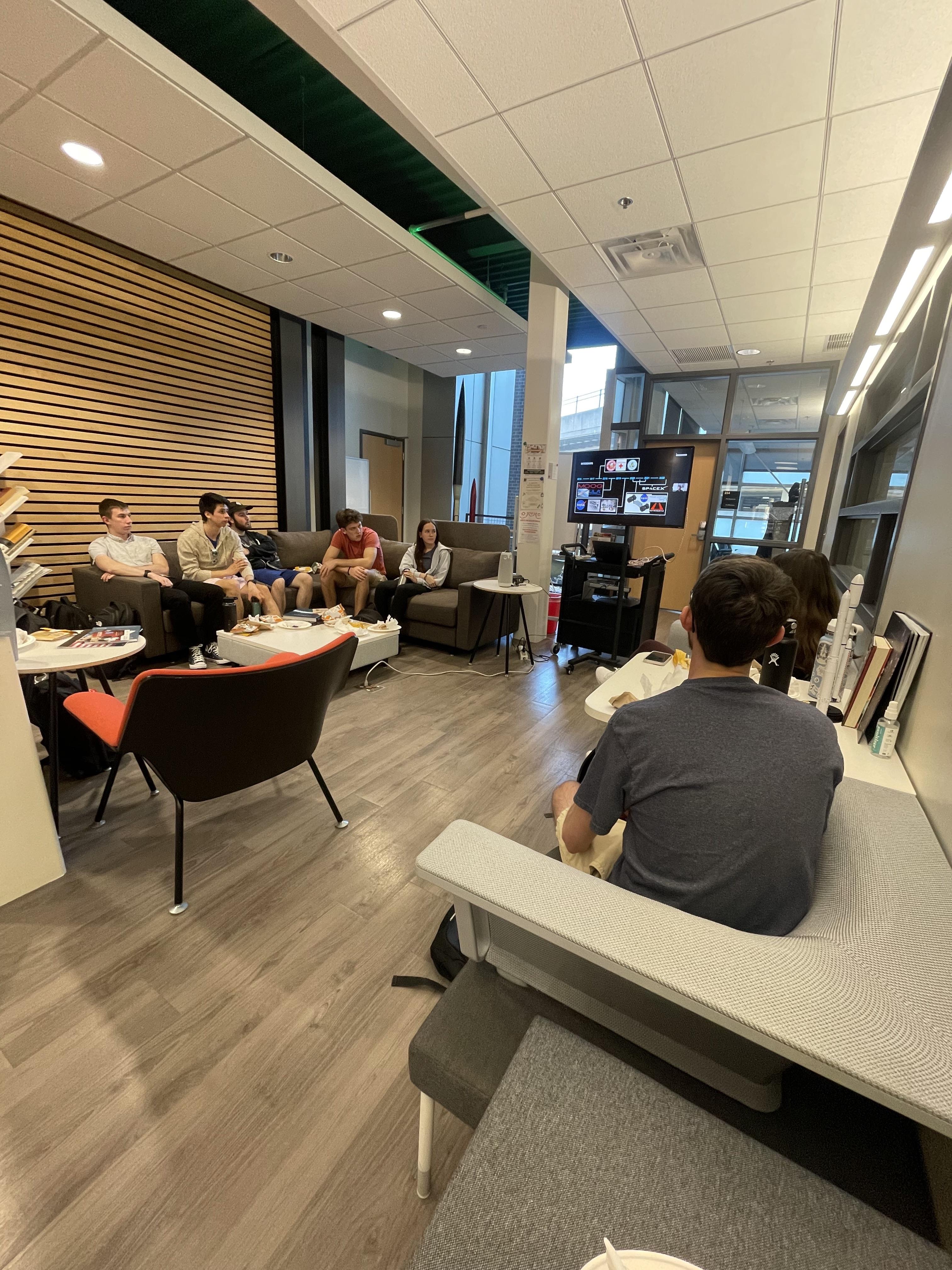 A group of students watching a presentation on a TV screen
