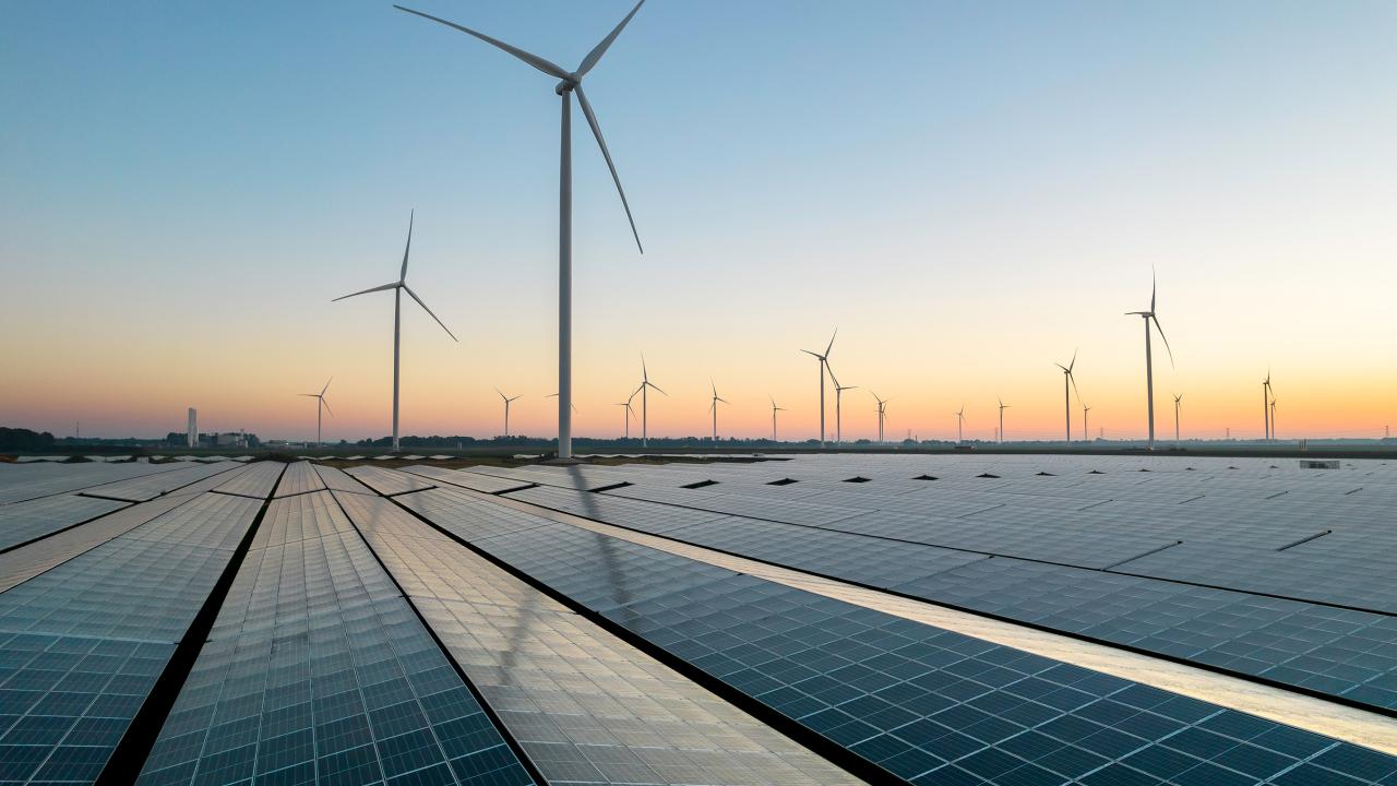 Windmills and solar panel field during sunrise
